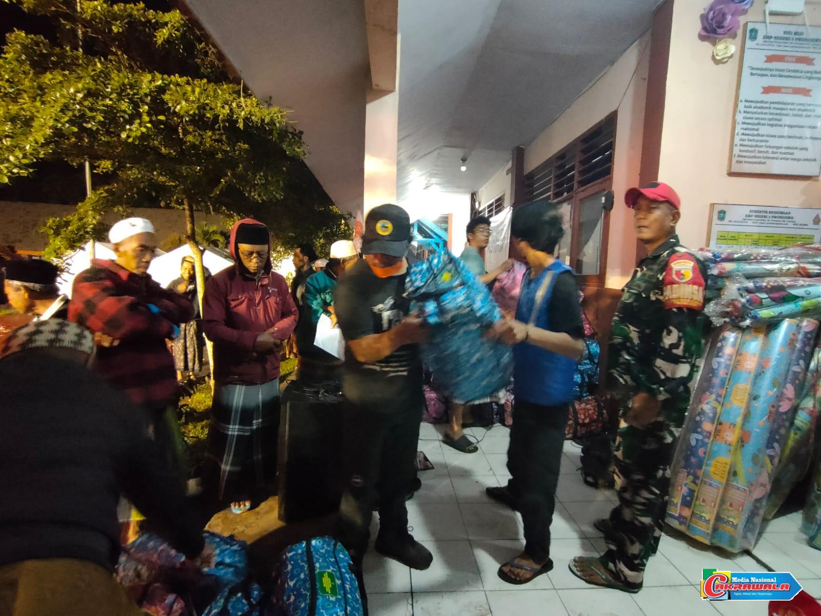Babinsa Oro-oro Ombo dan relawan membagikan paket sembako kepada para pengungsi erupsi Semeru di Posko SMPN 02 Pronojiwo.