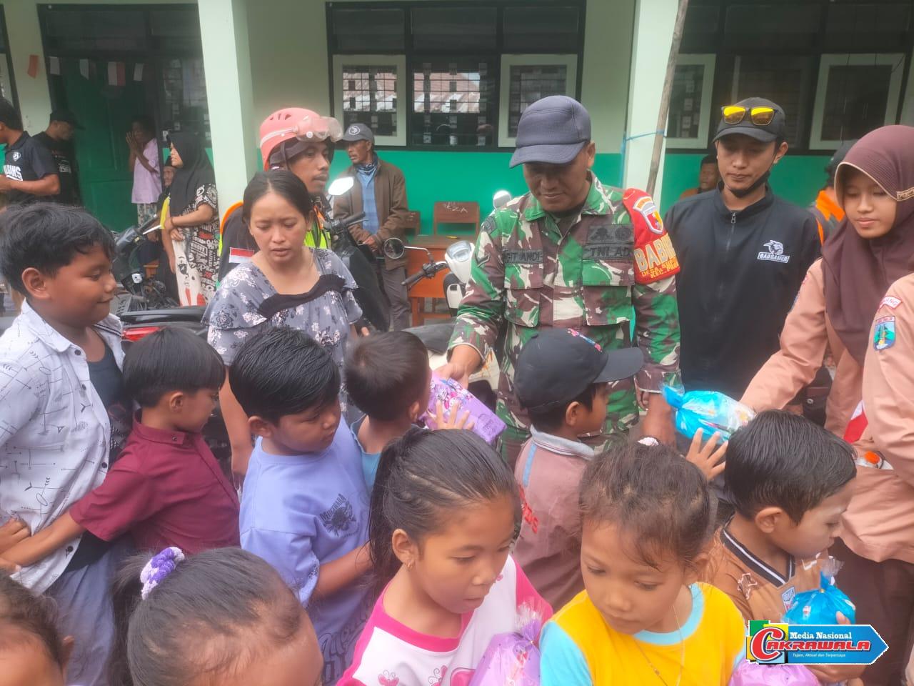 Babinsa Supiturang bersama guru dan relawan berbagi makanan ringan dan mainan untuk anak-anak di pengungsian SDN 04 Supiturang.