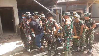 Personel TNI membantu warga dalam Pemulihan erupsi Semeru dengan membersihkan rumah tertimbun abu.